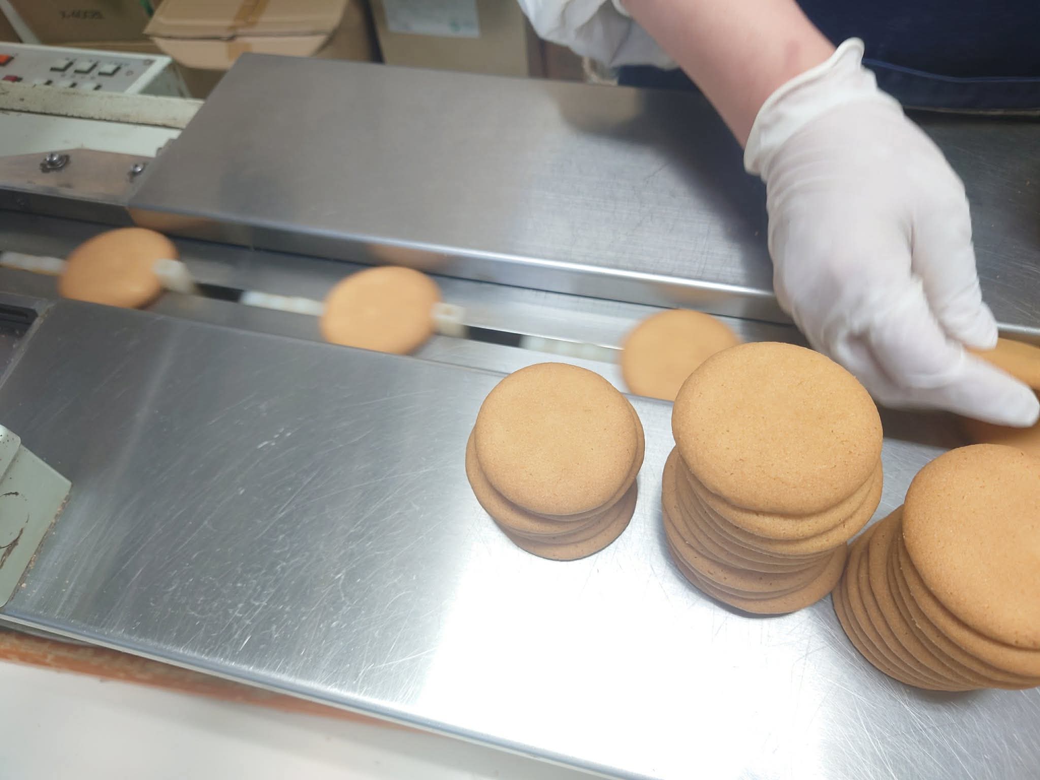 焼き上がったクッキーを検品し、個包装する工程